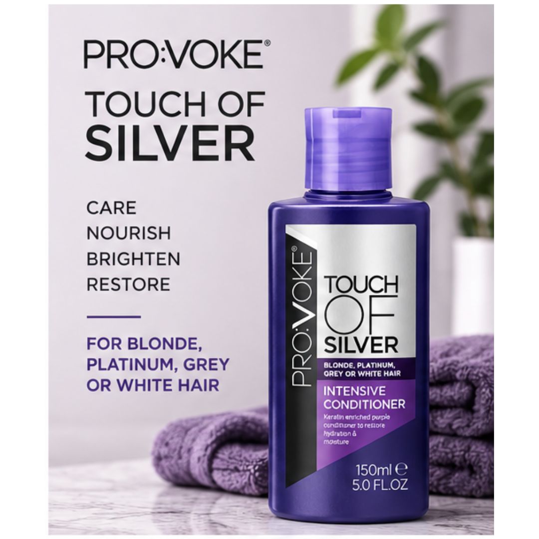 A bottle of Pro:Voke Touch of Silver Intensive Conditioner for blonde, platinum, grey, or white hair, shown next to folded purple towels and a blurred green plant on a light background.