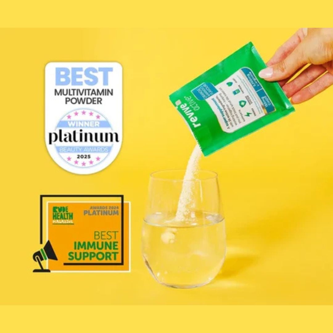 A hand pours white multivitamin powder from a green packet into a clear glass on a bright yellow background. Two award badges appear on the left: a white 'Best Multivitamin Powder Winner Platinum 2025' badge and an orange 'Best Immune Support' badge with Eye Health branding.