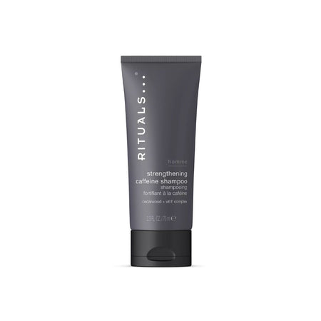 A dark gray squeeze tube of RITUALS... Strengthening Caffeine Shampoo with white text, set against a plain white background.