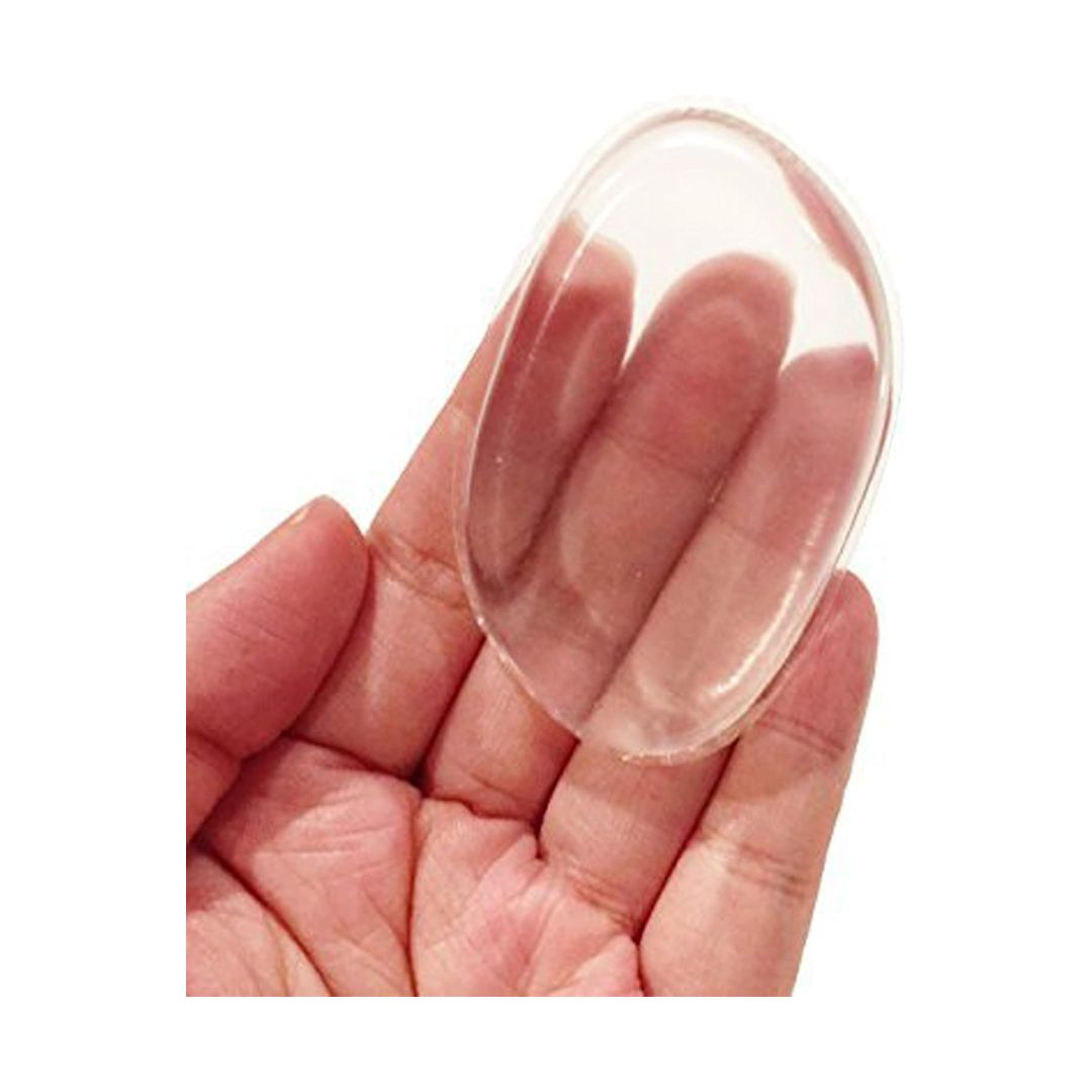 A clear, oval-shaped silicone or plastic nail tip being held in a person's hand against a plain white background.