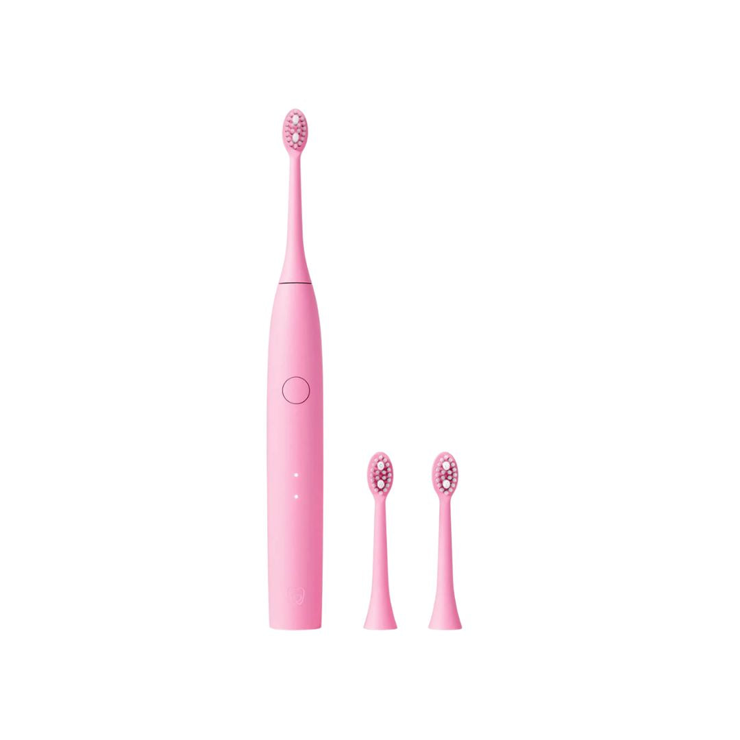 A pink electric toothbrush with two interchangeable brush heads, shown on a plain white background.