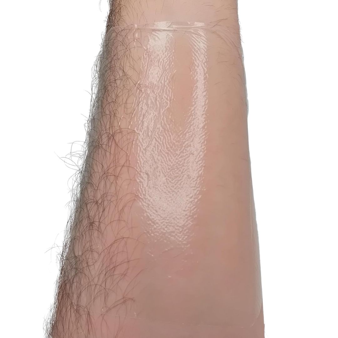 A tegaderm drssing after being applied to a leg with a white background