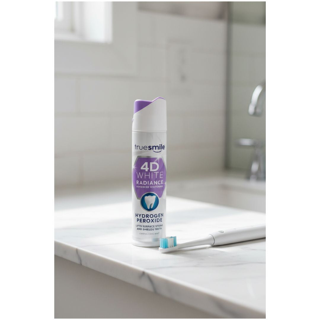 TrueSmile 4D White Radiance Hydrogen Peroxide Toothpaste on a white marble sink with a toothbrush