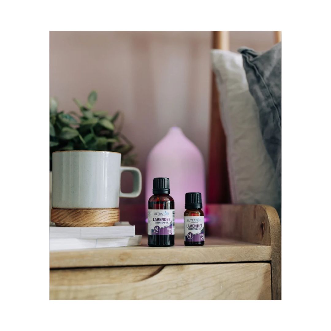 Ultrapure Lavender Essential Oil 10ml container on a wooden bedside cabinet with a bed in the background