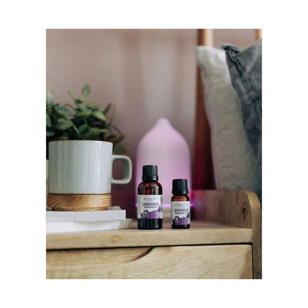 Ultrapure Lavender Essential Oil 10ml container on a wooden bedside cabinet with a bed in the background