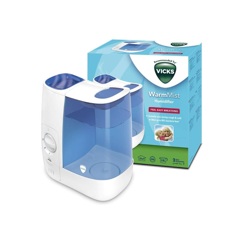 A Vicks WarmVist Humidifier shown in front of its retail packaging box on a clean white background. The humidifier is white with a translucent blue water tank and blue top tray.