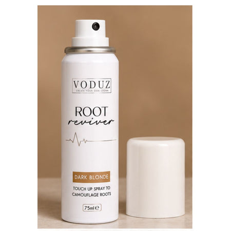A white VODUZ Root Reviver touch-up spray canister with its cap off, displayed next to it on a light wooden surface against a solid tan background.