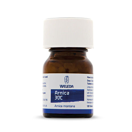 A small amber glass bottle of Weleda Arnica 30C tablets with a white screw cap and a white label featuring blue text and branding, shown on a clean white background.