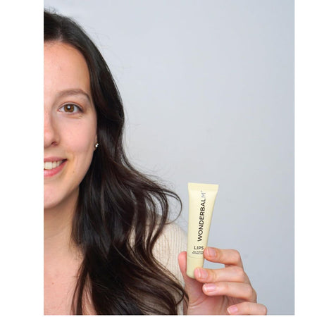 Wonderbalm The Wonder Duo Gift Set - lip balm being held up by a woman on a grey background