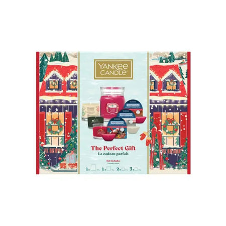 Yankee Candle 'The Perfect Gift' advent calendar set, featuring a festive holiday illustration of snow-covered houses on the sides and a central display of various candle products including a large jar candle and smaller tins.