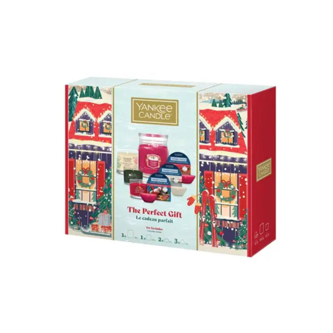 Yankee Candle 'The Perfect Gift' advent calendar box, featuring a festive winter village illustration with red houses, green trees, and a central window displaying candles and gift boxes.