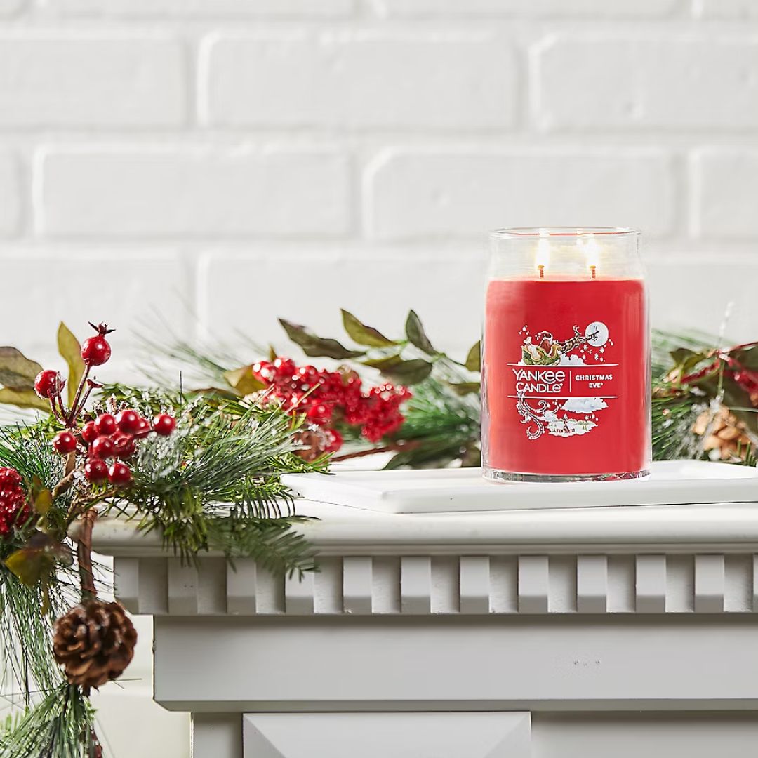 Yankee Large Christmas Eve Candle Jar on a mantlepiece decorated with christmas garland
