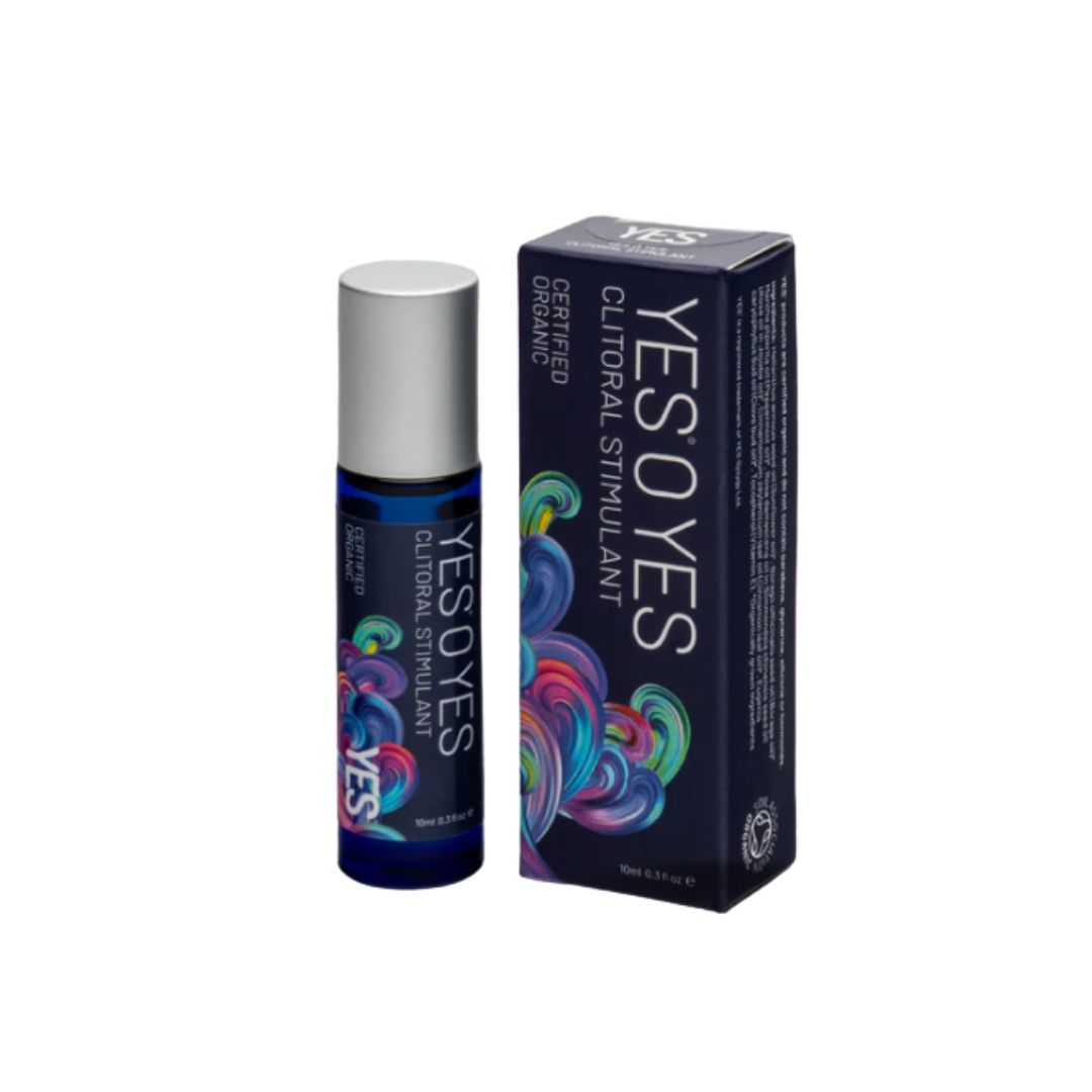 A roll-on bottle and its matching box of YES YES Certified Organic Clitoral Stimulant, featuring a dark blue and black design with vibrant multicolored swirls and a silver cap.