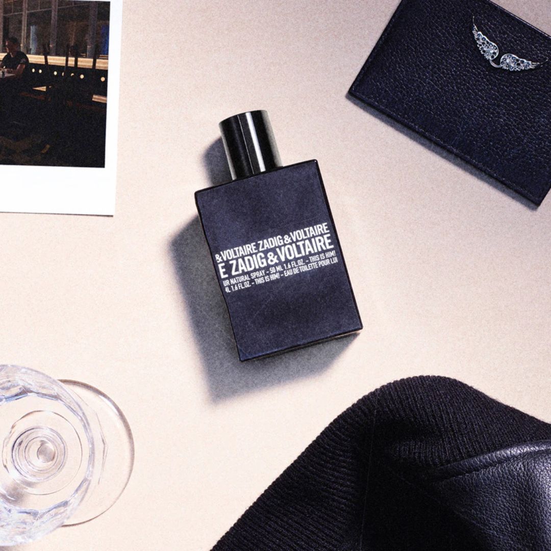 Perfume bottle by E. Zadig & Voltaire on a light surface with a black card and sweater.