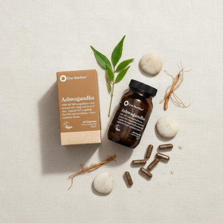 One Nutrition Ashwagandha supplement packaging with capsules and roots on a light background