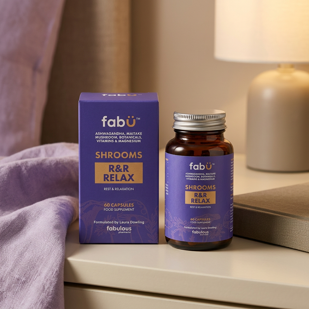 A bottle and box of fabür Shrooms R&R Relax capsules placed on a bedside table next to a lamp, with a purple blanket in the foreground.