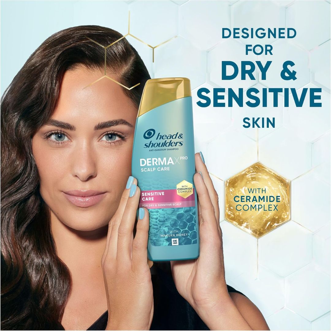 Woman holding a bottle of Head & Shoulders Derma Pro Scalp Care for dry and sensitive skin.