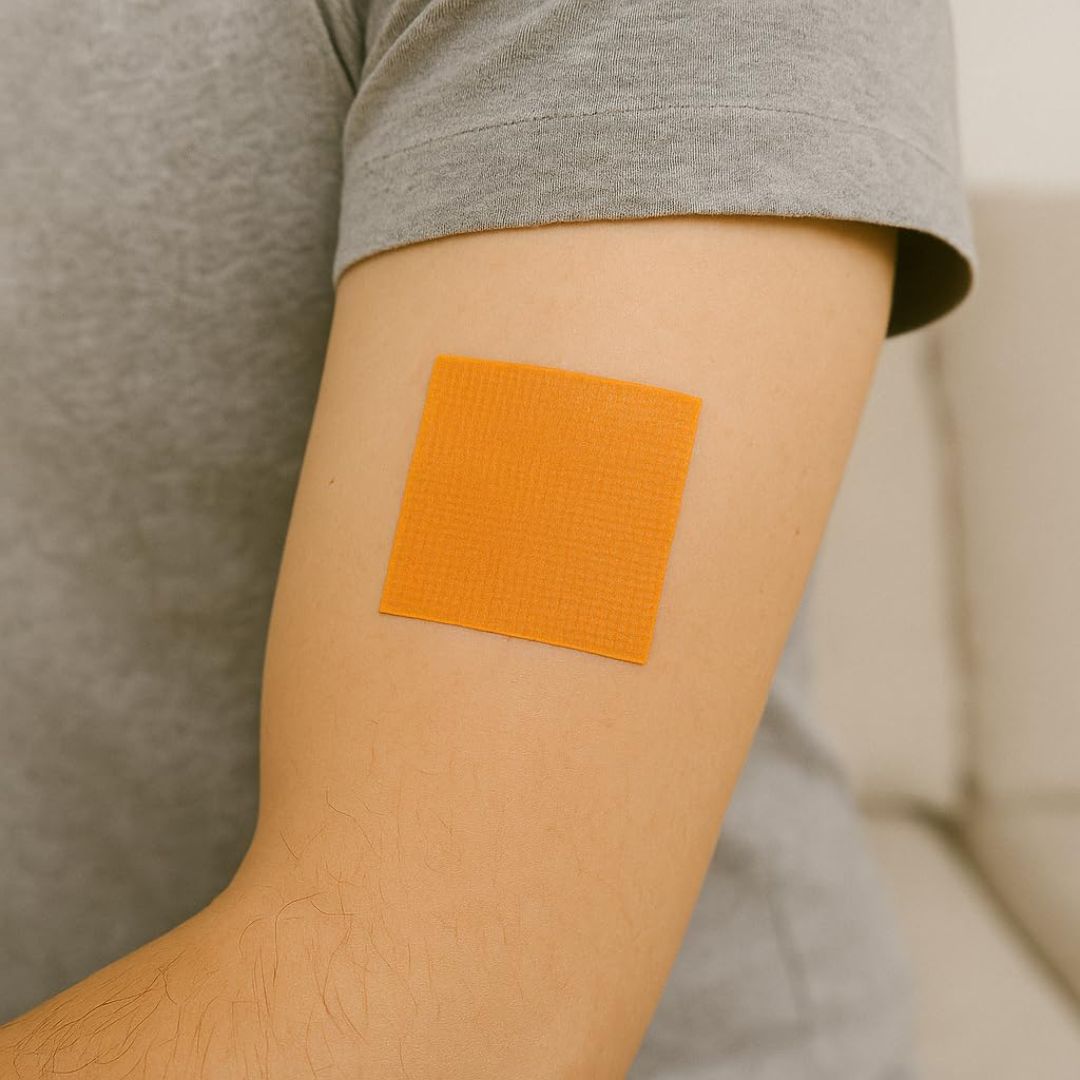 Orange adhesive patch on a person's arm with a neutral background