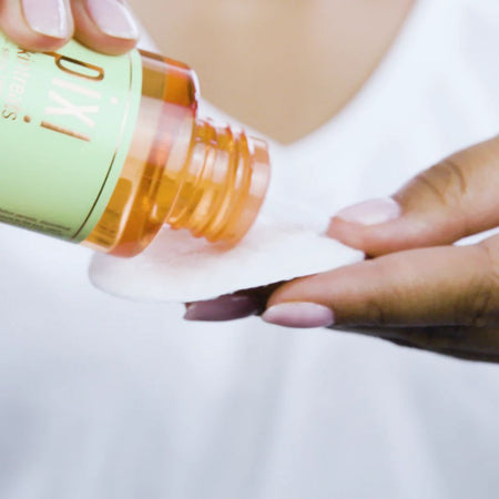Person pouring medication from a bottle onto a white surface